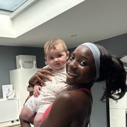 Rosae, the coach, smiling as she holds a baby in the studio