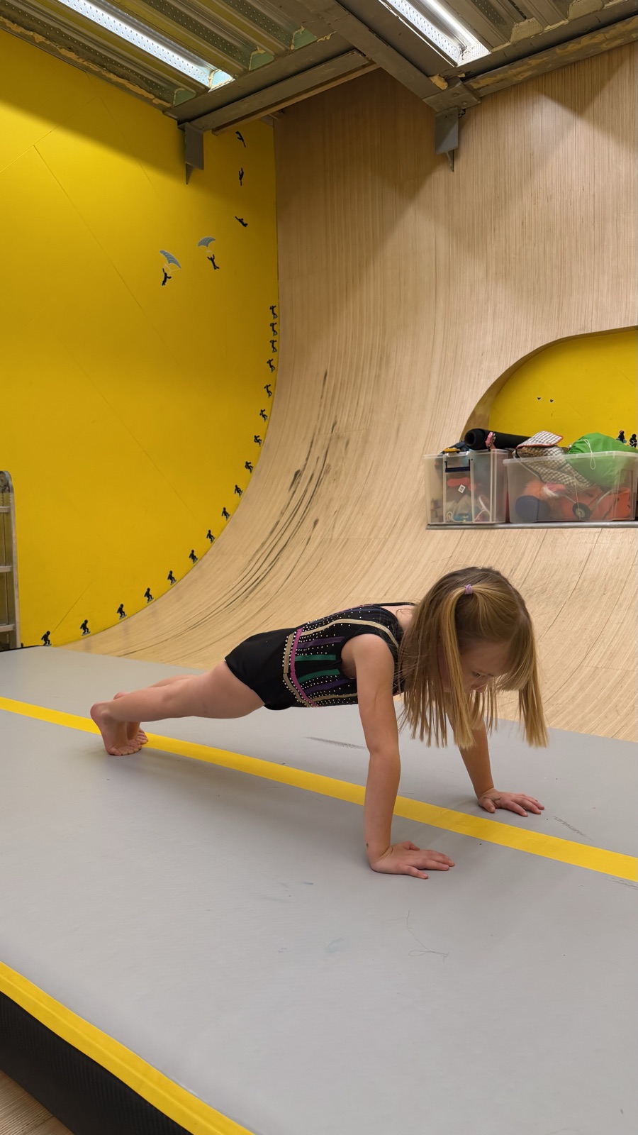 A young gymnast holding a plank conditioning hold on the air-track