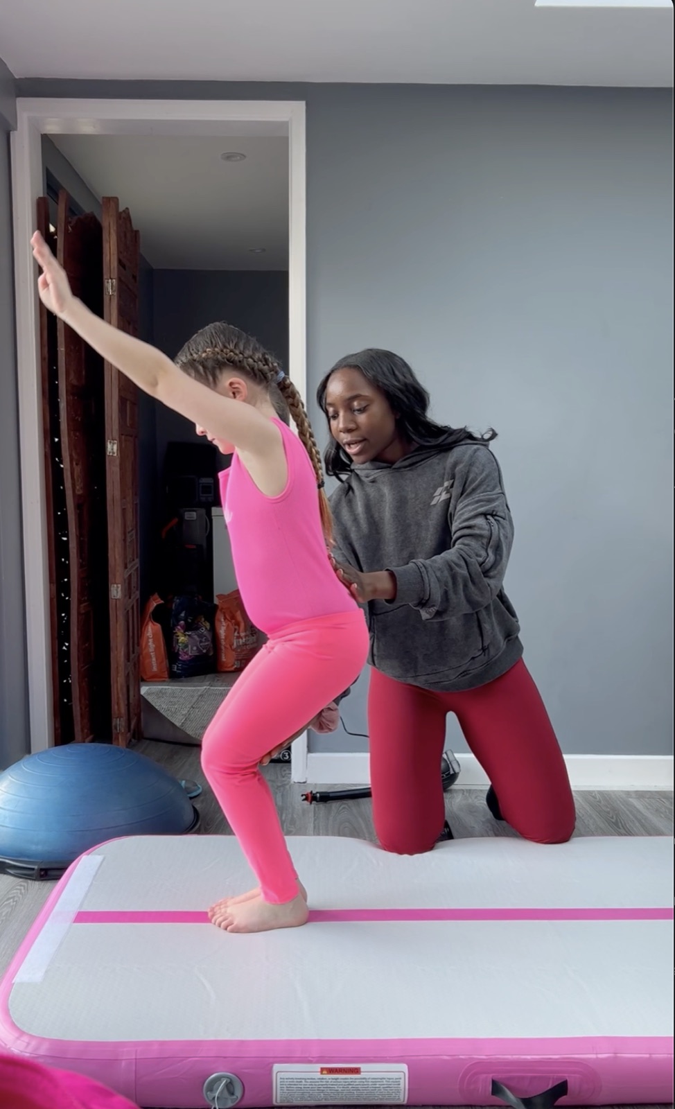 Rosae spotting a young gymnast in a floor pose on the air-track